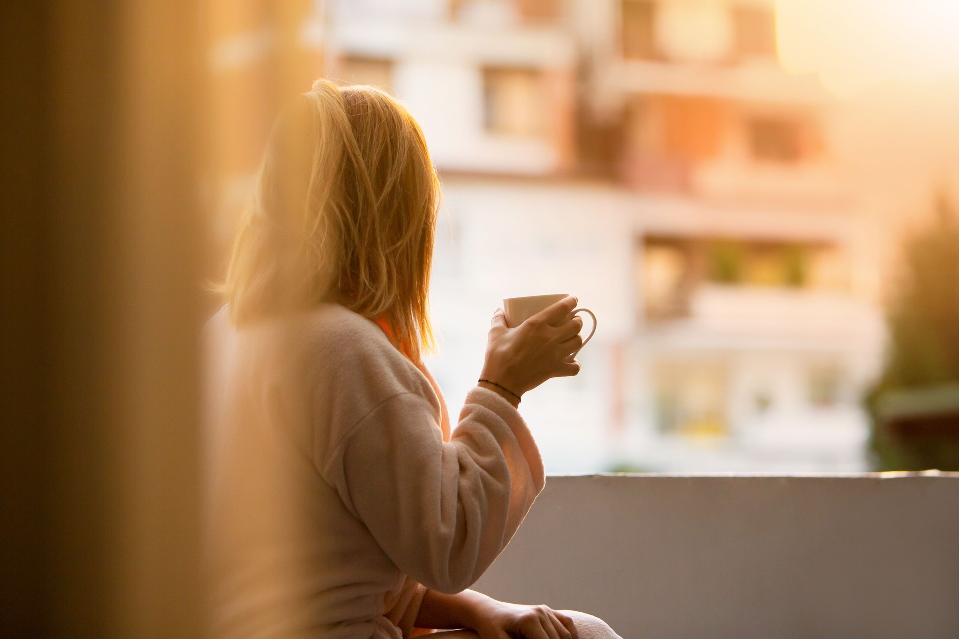 Morning Tranquility: Woman Sips Coffee on Balcony, Ready for the Day